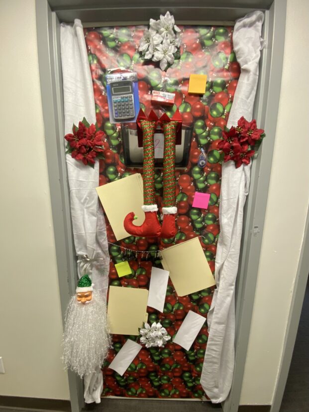 Christmas door decorating entry number 2: The Accounting Door with Santa hanging from the file slot, papers, receipts, calculator, and post its as decorations