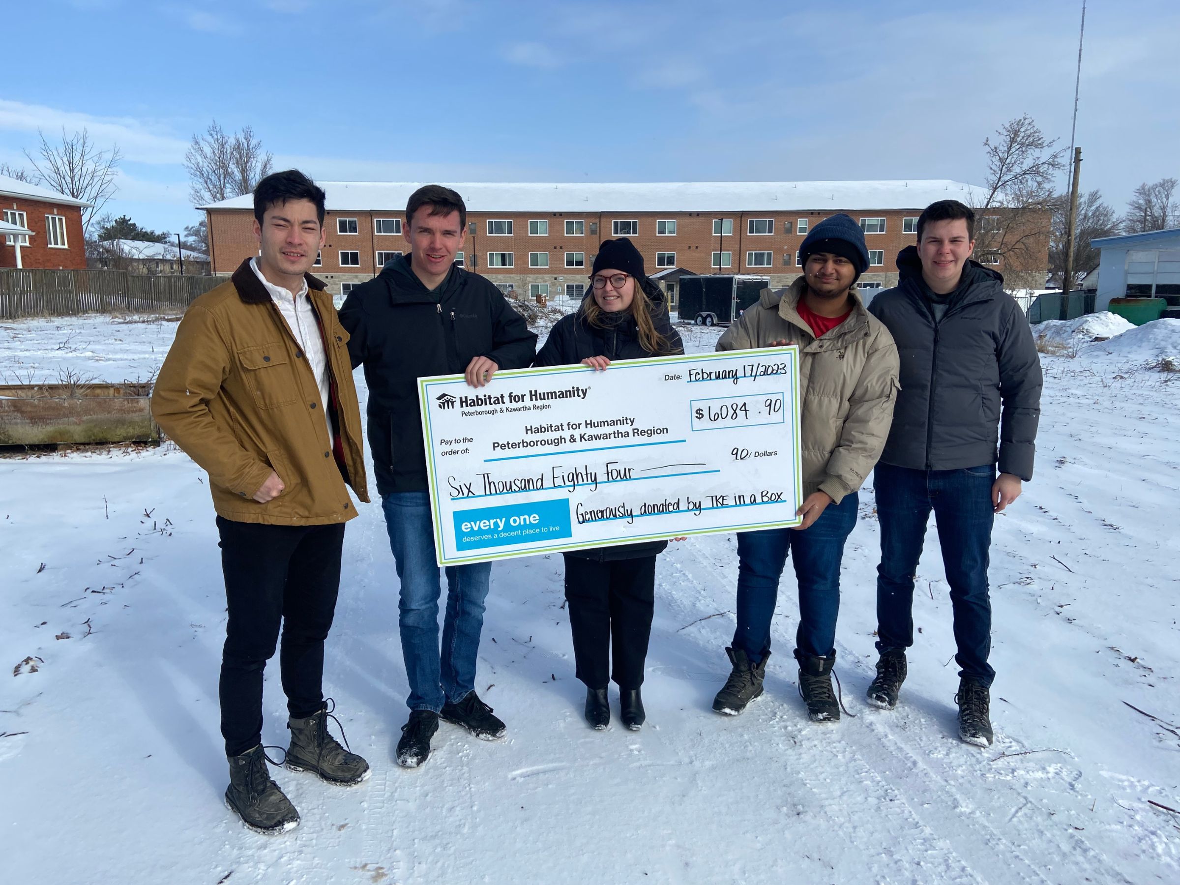 TKE members with Communications & Donor Services Manager Jenn Macdonald receiving a cheque from the TKE in A Box fundraiser. Photo taken in front of the Phase 2 site of Leahy's Lane