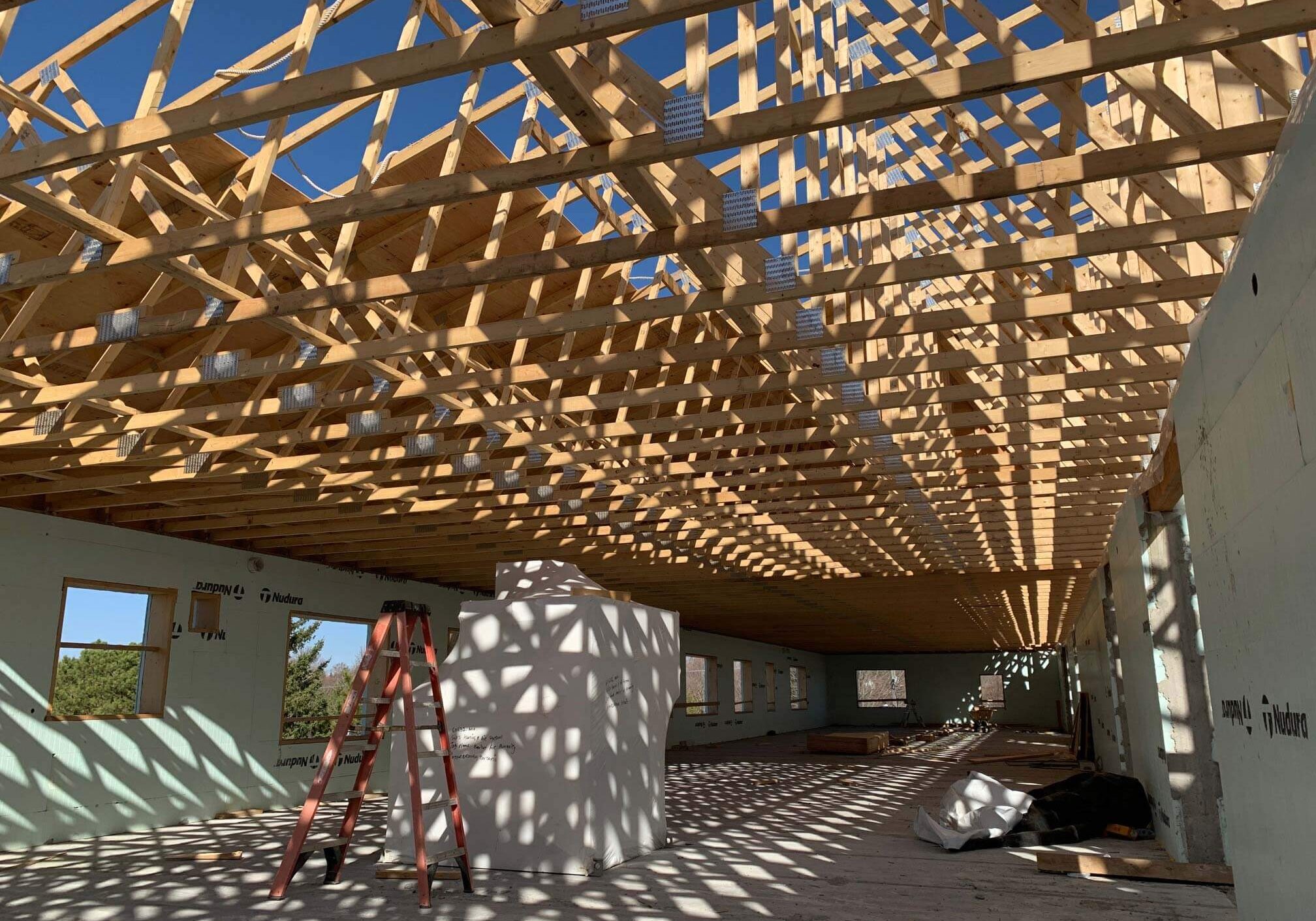 A shot from inside an under construction home build, sunlight is filtering through the exposed framing